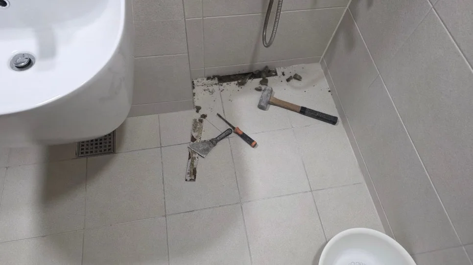 위층 화장실 샤워기 아래 바닥을 부분 개방해 누수를 점검하는 현장